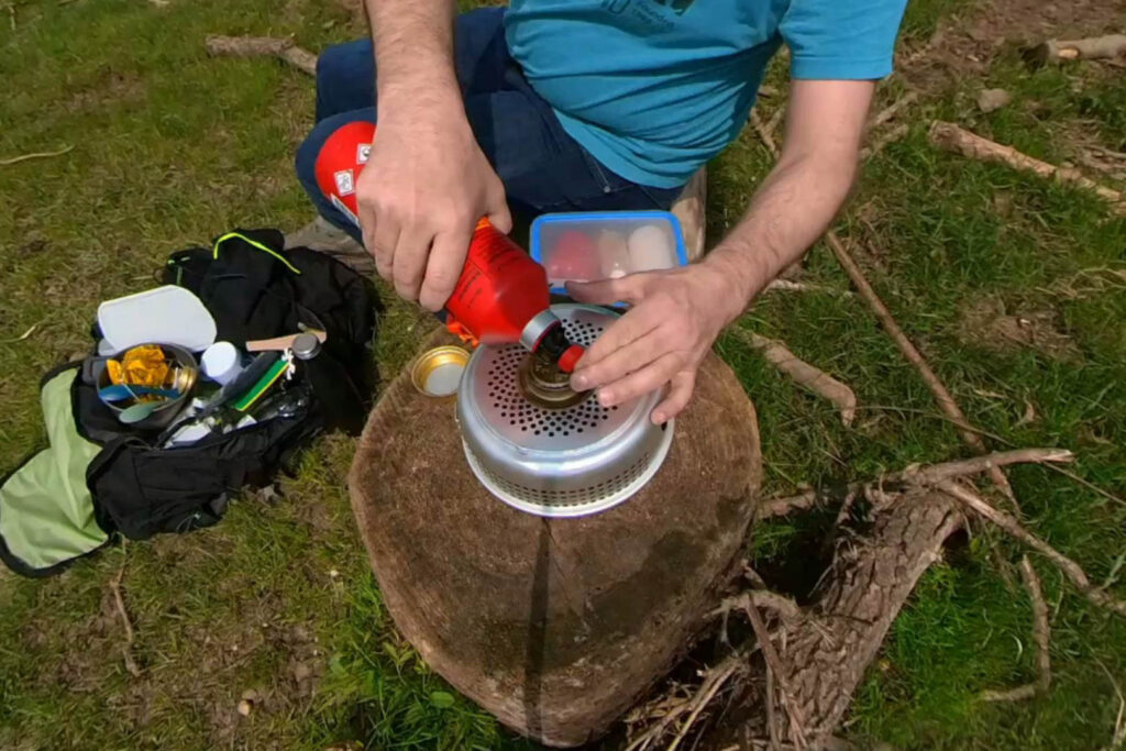 Befüllung des Trangia auf einem Holzklotz